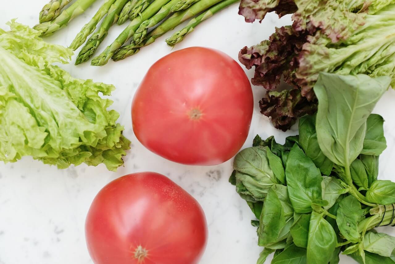 Fresh tomatoes, asparagus, lettuce, and basil on a white background