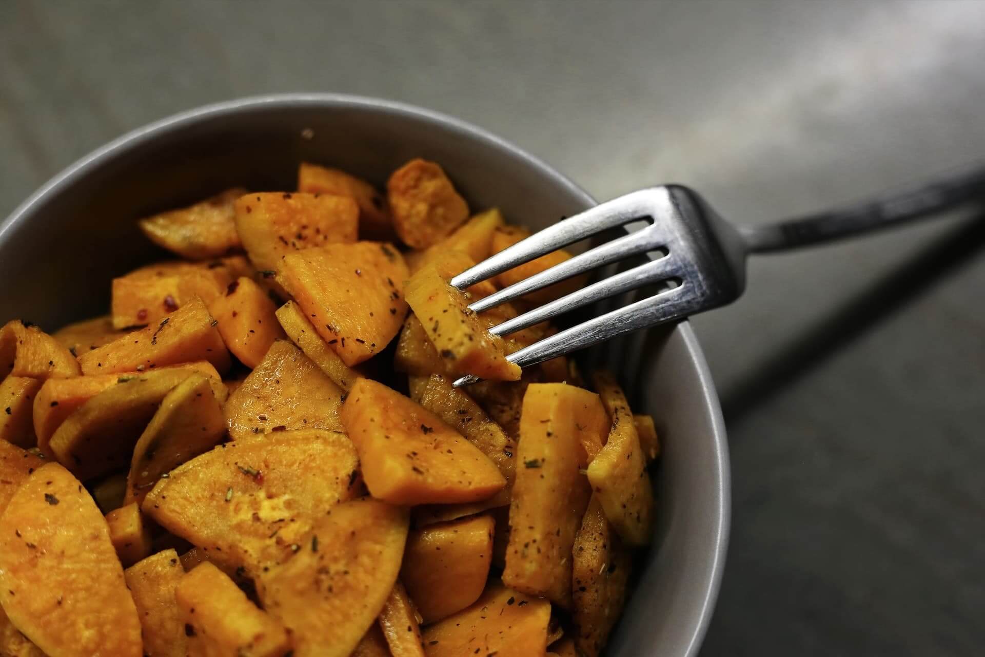 Roasted butternut squash cubes with herbs in a white bowl