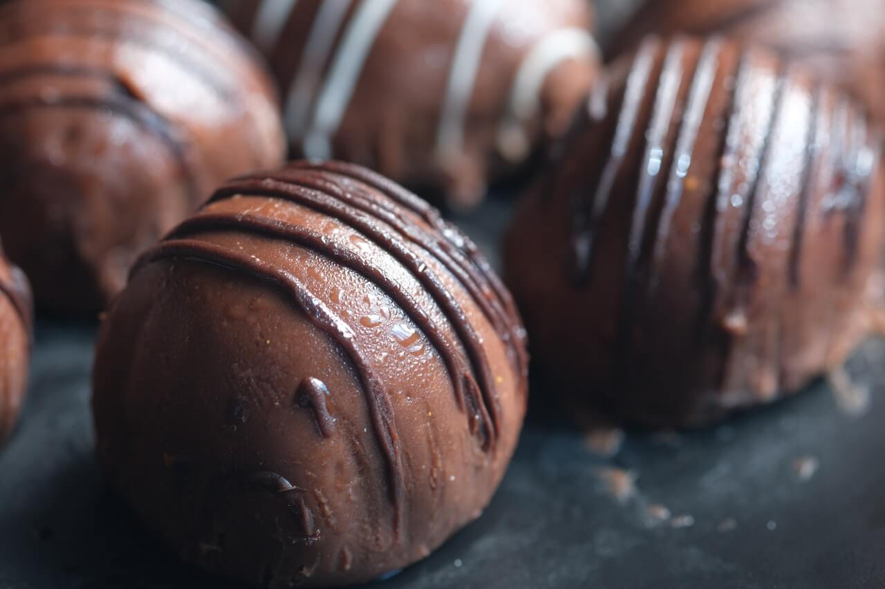 Glossy chocolate truffles with drizzled dark chocolate coating