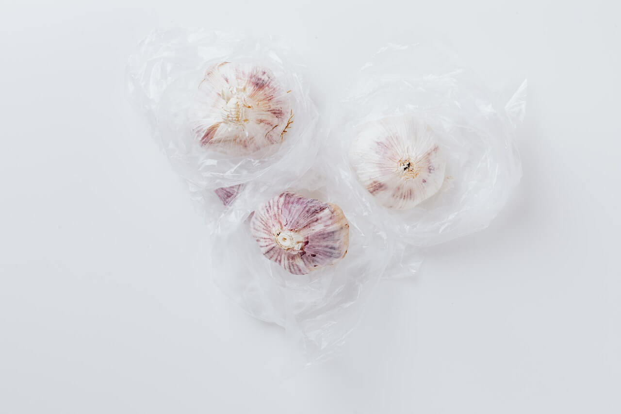 Three fresh garlic bulbs wrapped in delicate translucent material