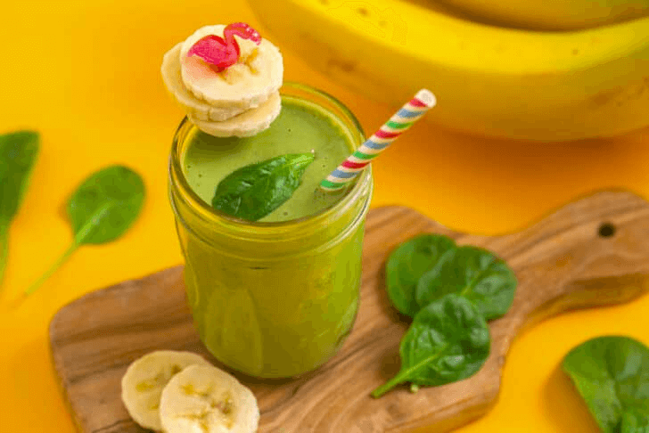 Green smoothie with banana, spinach, colorful straw in mason jar
