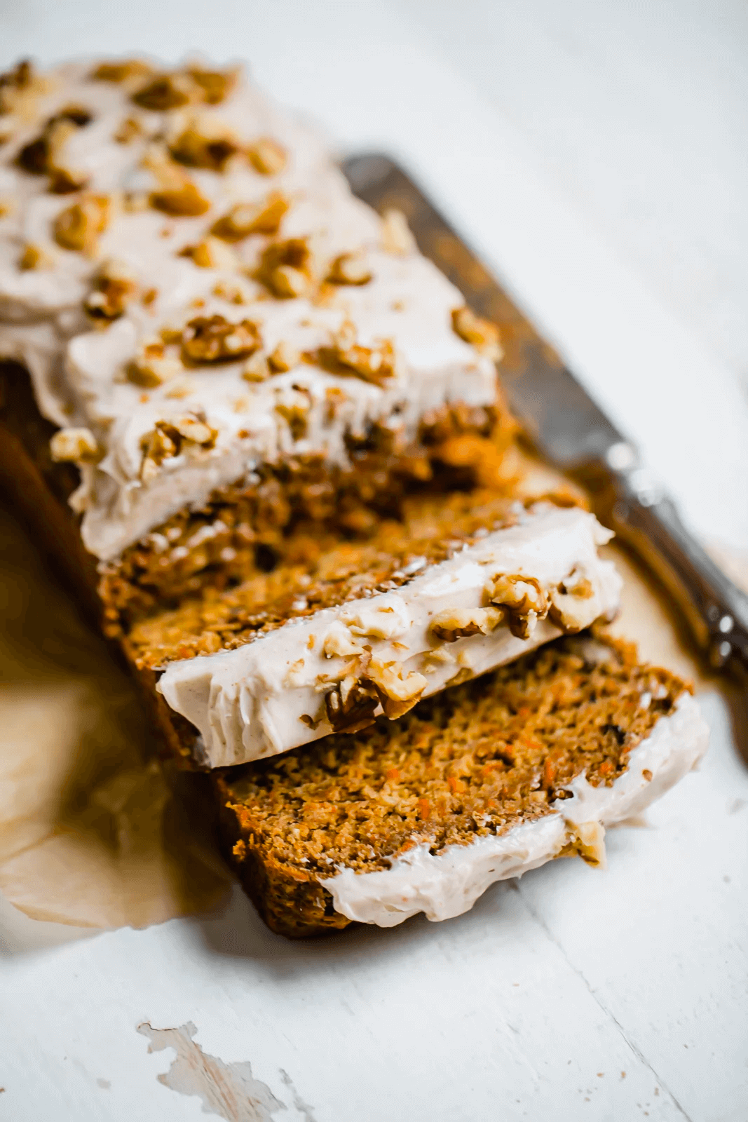 Sliced carrot cake with cream cheese frosting and chopped walnuts