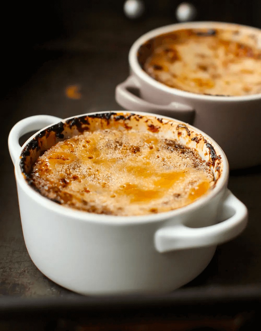 Golden-brown crème brûlée in white ceramic ramekins with caramelized top