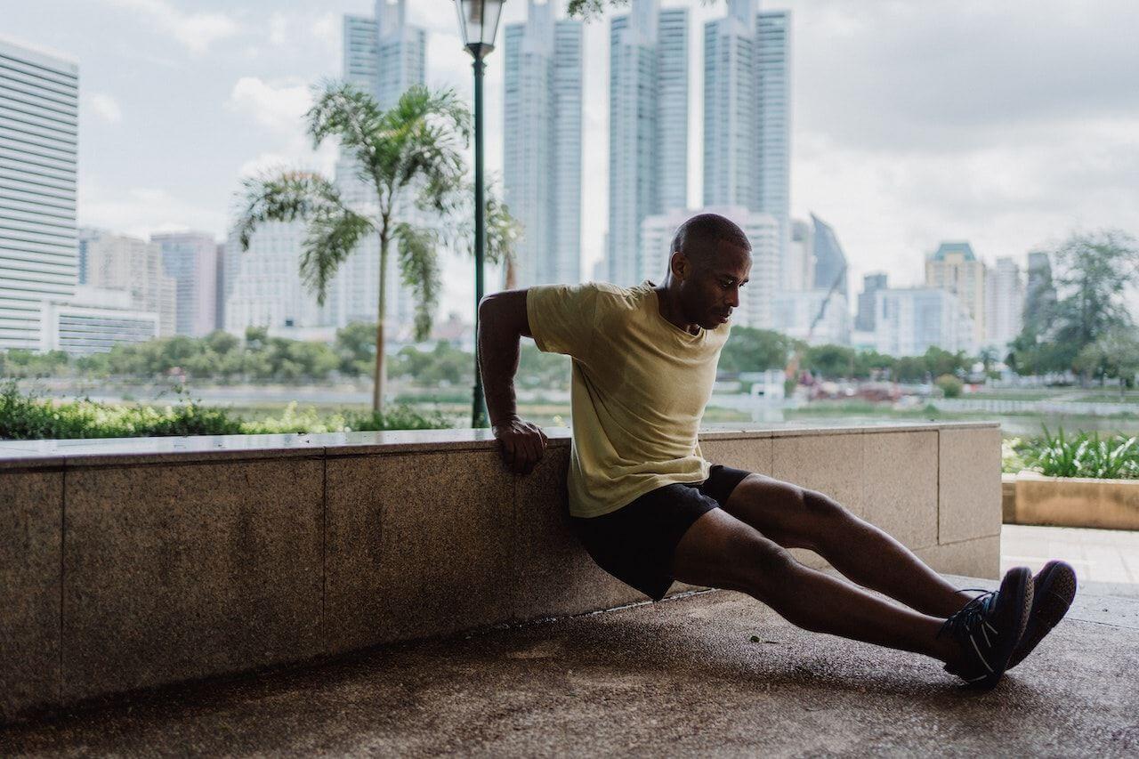Athlete doing tricep dips with urban skyline in background