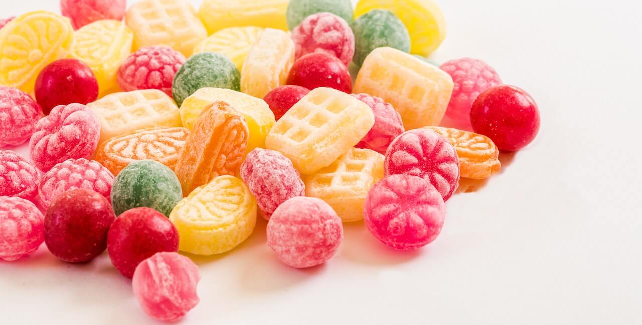 Colorful gummy candies including raspberries, citrus slices, and sour sugar-coated fruit pieces