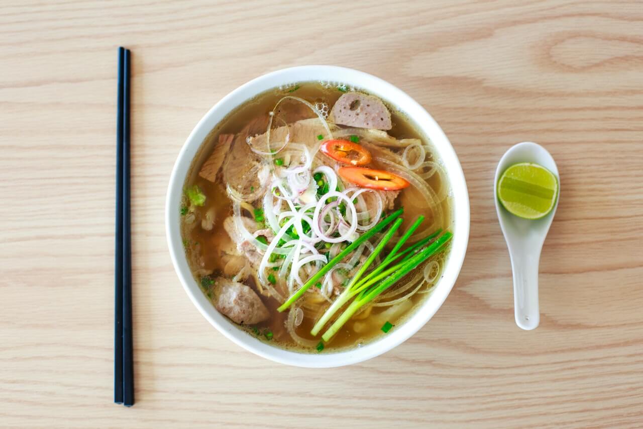 Vietnamese pho soup with meatballs, noodles, herbs, and lime