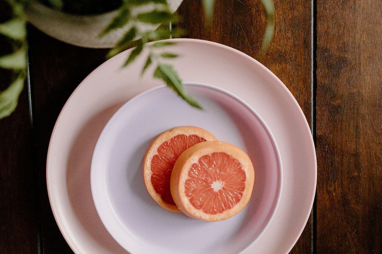 Halved pink grapefruit on pastel plates with green leaves