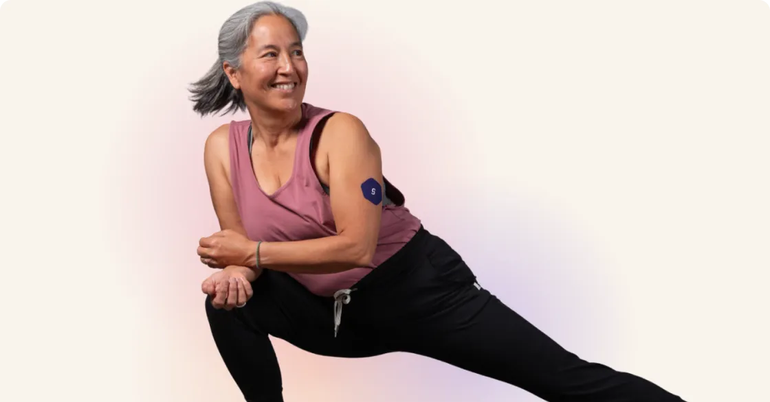 Older woman in pink top doing dynamic stretching exercise with a smile