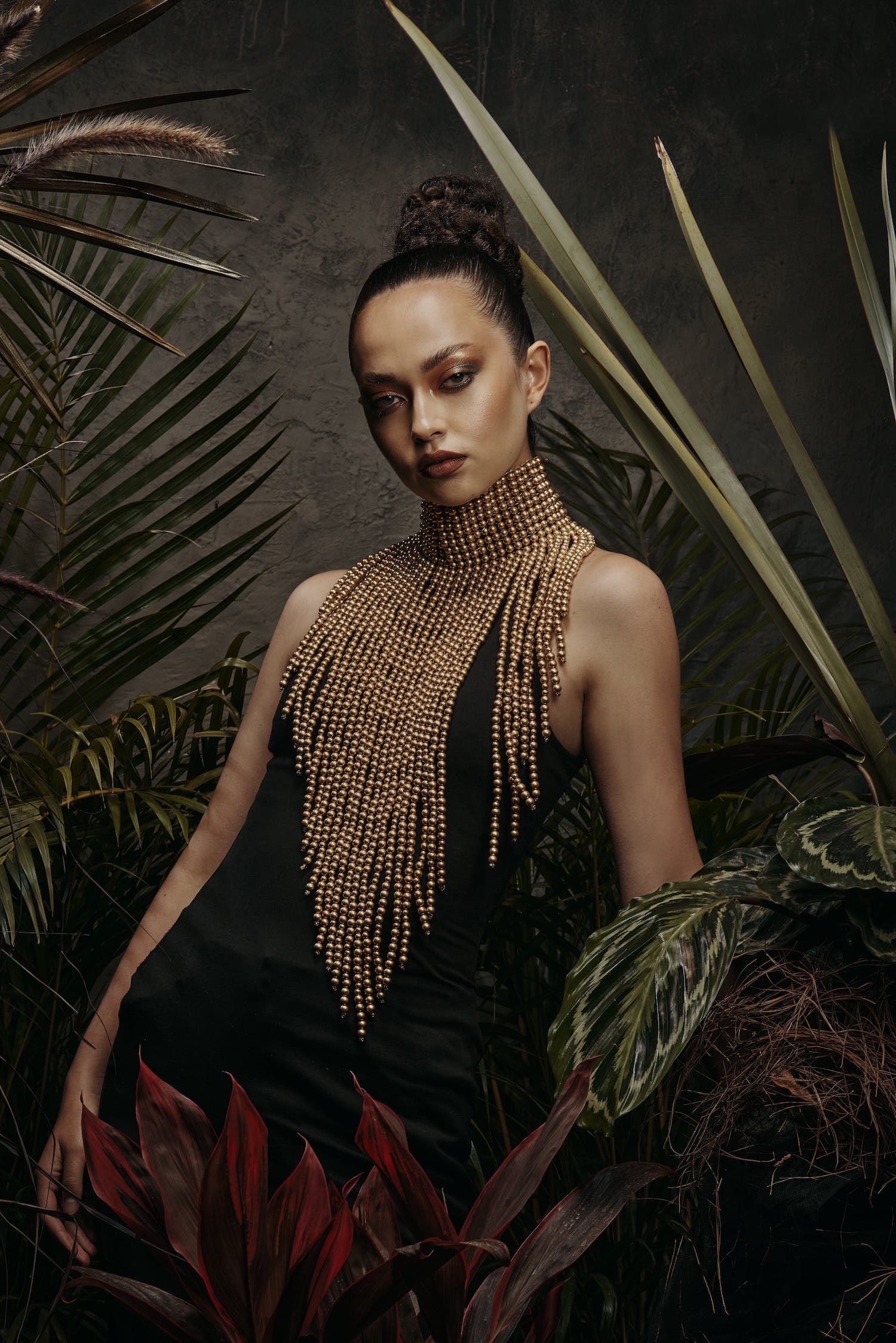 A mysterious and alluring woman wears a daring piece of jewelry that perfectly blends elegance with chic and sexy vibes. Made from a fusion of beads and feathers, the piece is a true work of art that exudes culture and luxury.