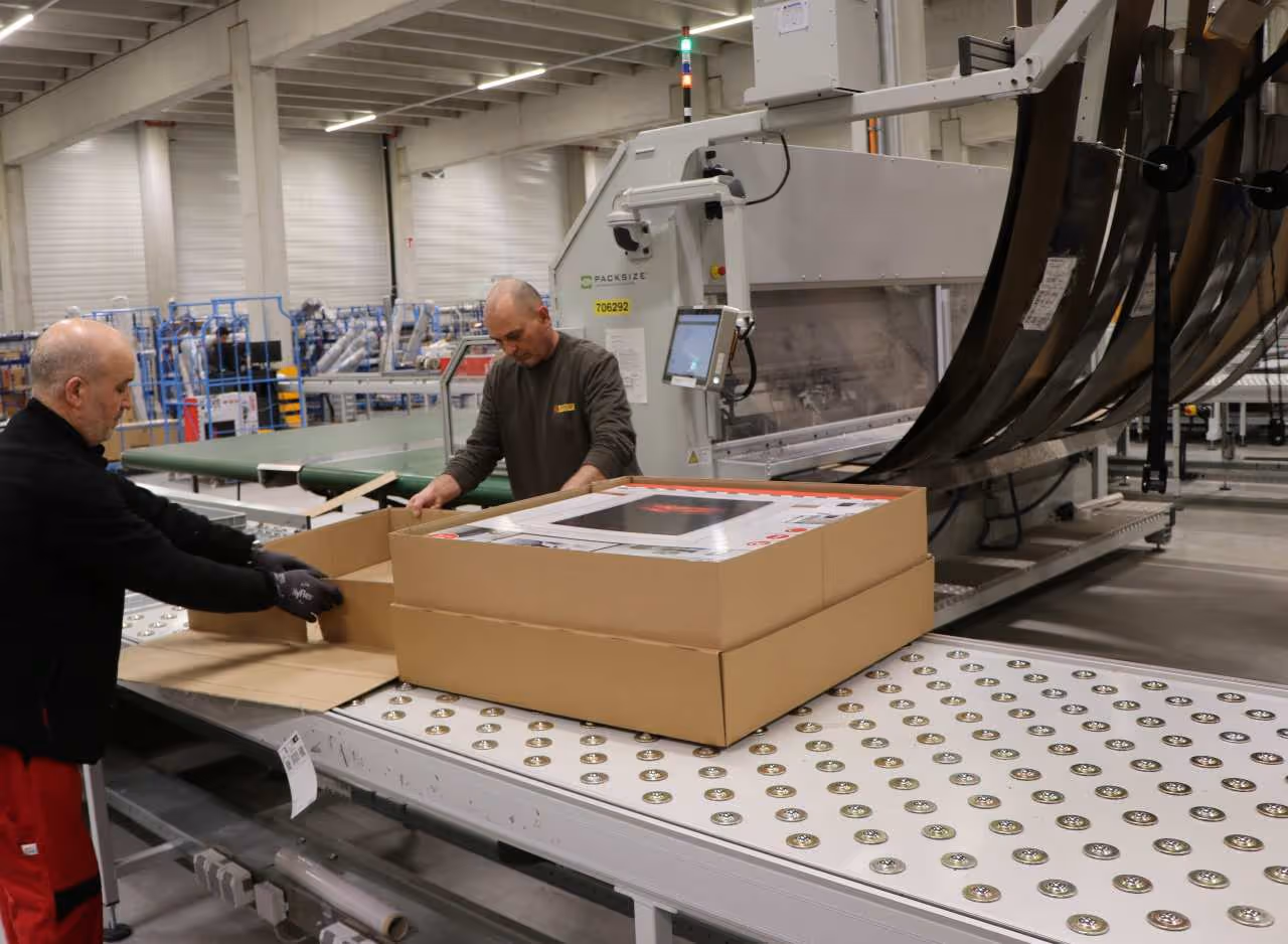 POCO-Mitarbeiter verpacken einen Kamin im maßgenauen Karton - ohne Luft und mit optimalem Produktschutz.