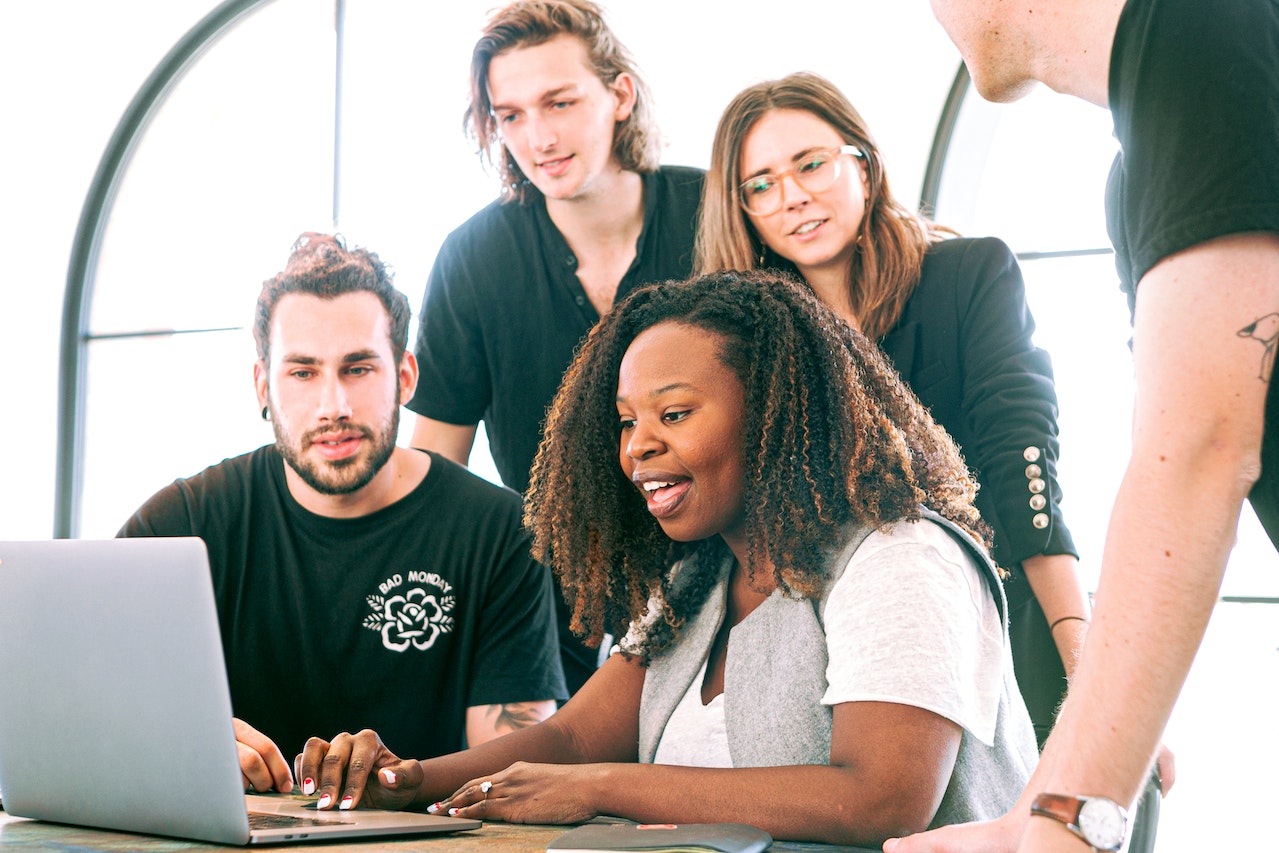 Employees gathered around a computer smiling