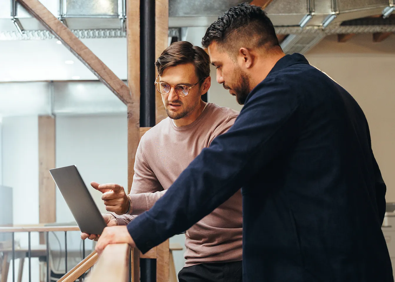 Two men work with a vendor management solution on a laptop computer.