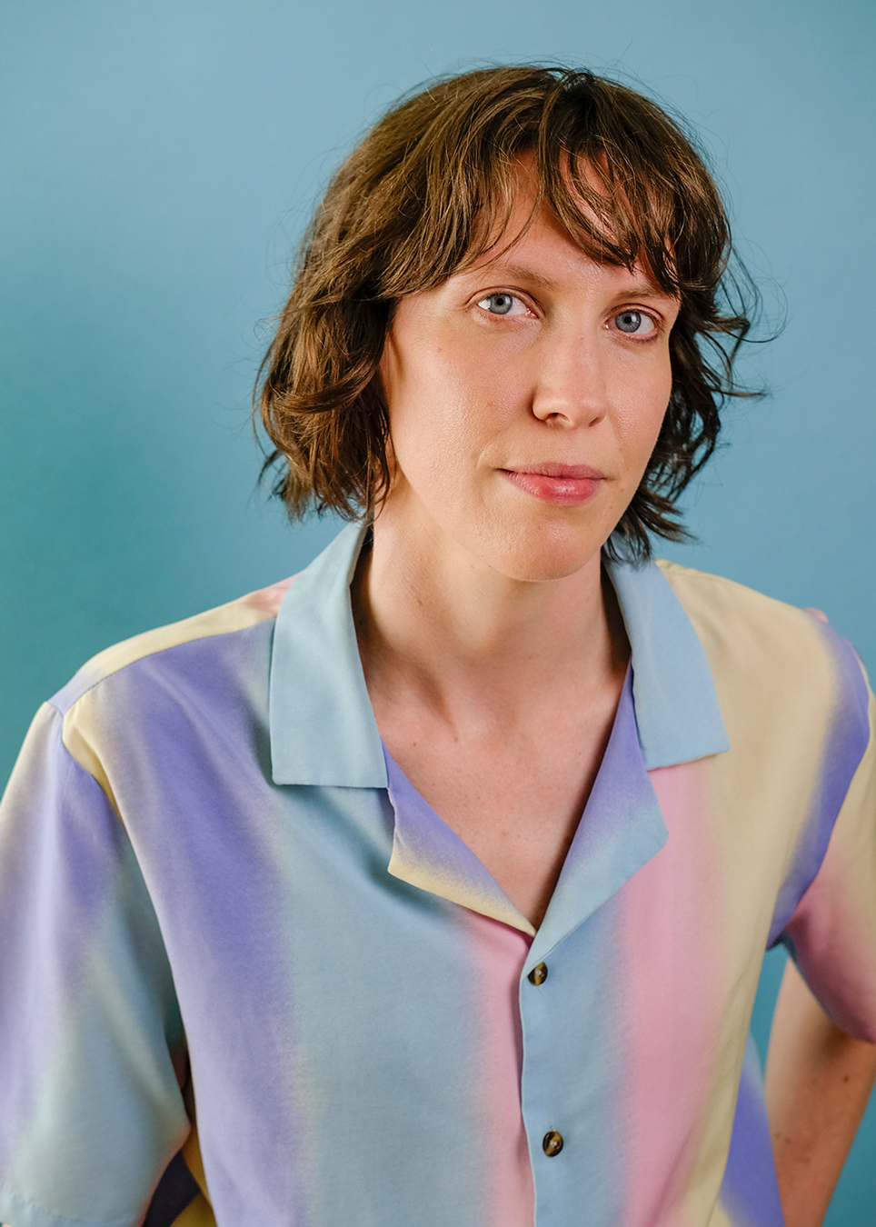 Still life of oranges, limes and avocados against a green backdrop.