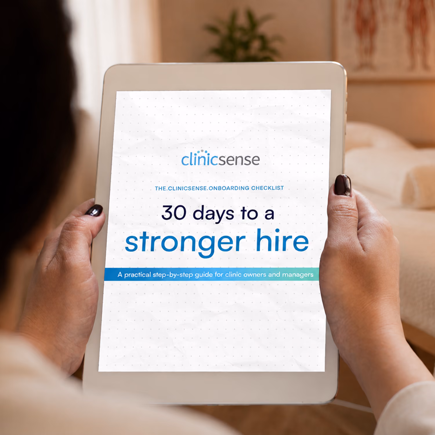 Hands holding a tablet displaying the ClinicSense onboarding checklist cover, 30 days to a stronger hire.