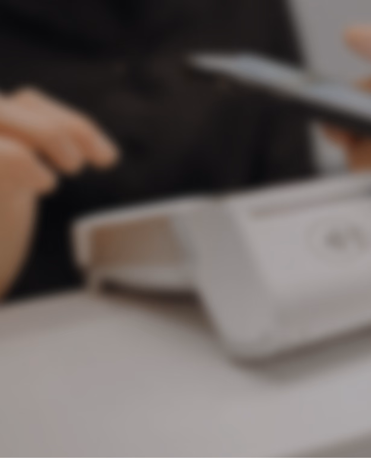 Blurred background photo of hands near a contactless card payment terminal.