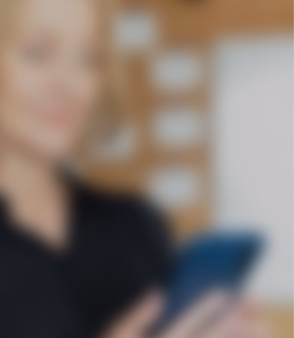 Blurred background photo of a smiling woman holding a phone in a clinic setting.