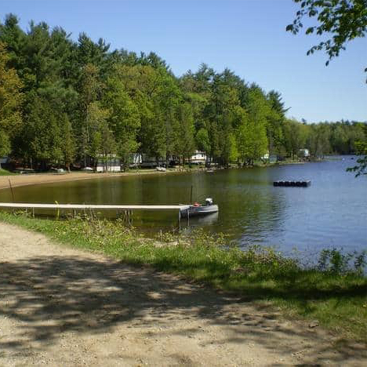 A campground with chairs around a fire near a lake