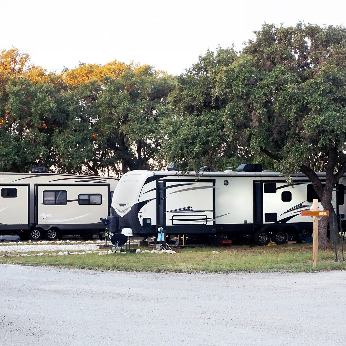 A campground with chairs around a fire near a lake