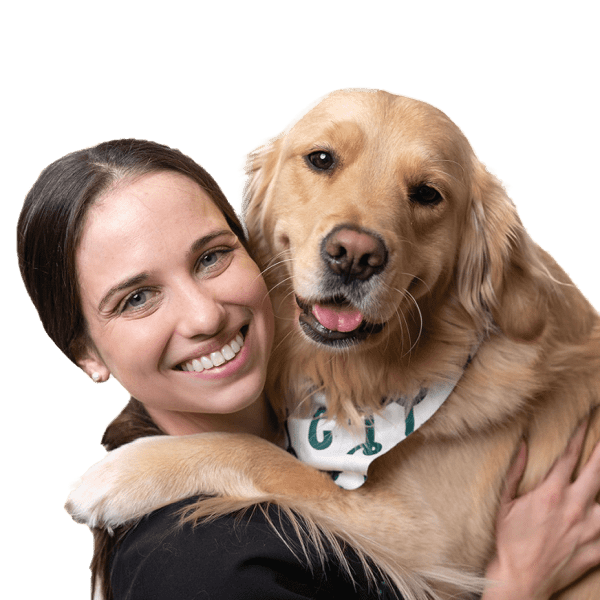 Dr. Cassandra is smiling warmly, showing kindness and professionalism as she hugs a golden retriever.