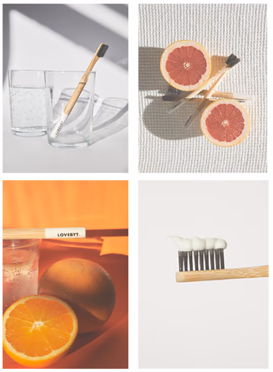 Collage of four images featuring a bamboo toothbrush with black bristles: in a clear glass with a second glass behind it, lying on a textured white surface alongside two grapefruit halves, resting on an orange surface with a whole and half orange, and showing the toothbrush close-up with white toothpaste on bristles.