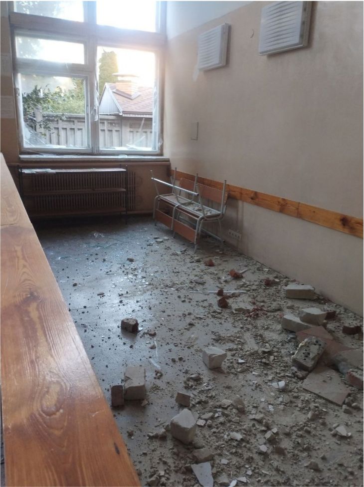 A classroom with blown-out windows and rubble on the floor after a missile strike