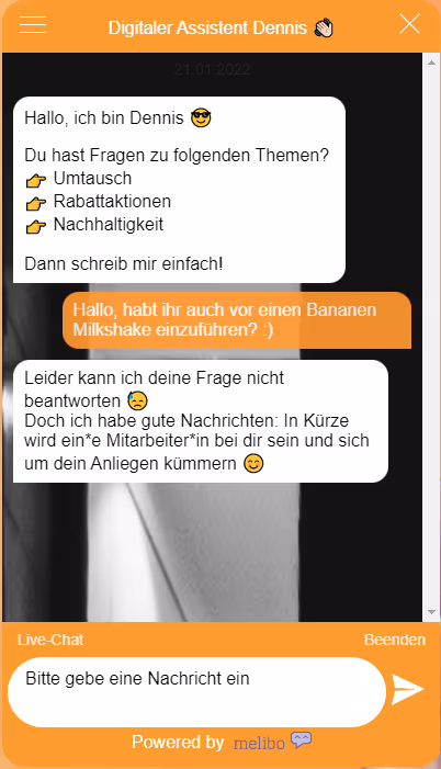 Screenshot des Chatfensters „Digitaler Assistent Dennis“: Begrüßung mit Themen Umtausch, Rabattaktionen, Nachhaltigkeit; Nutzer fragt nach einem Bananen-Milkshake; Bot kann nicht antworten und kündigt Übergabe an einen Mitarbeitenden an; unten Bereich Live-Chat mit Eingabefeld „Bitte gebe eine Nachricht ein“.