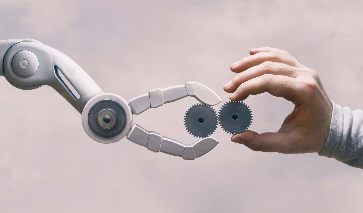Roboterarm und menschliche Hand richten zwei Metallzahnräder aus.