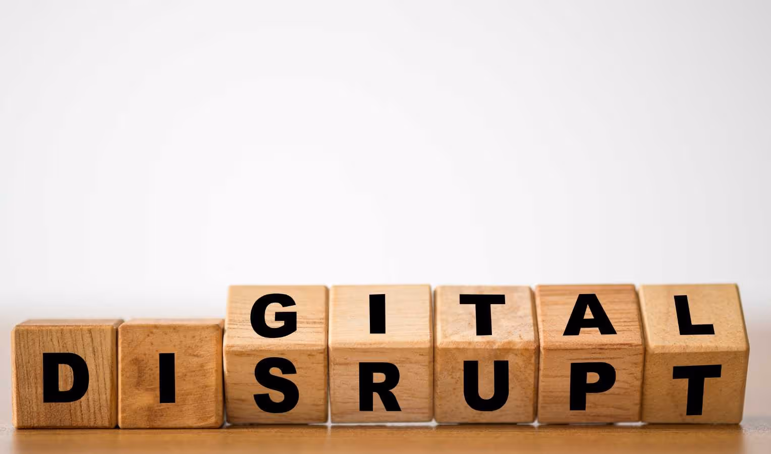 Holzklötze mit schwarzen Buchstaben formen „DIGITAL DISRUPT“ – Symbol für digitale Disruption.
