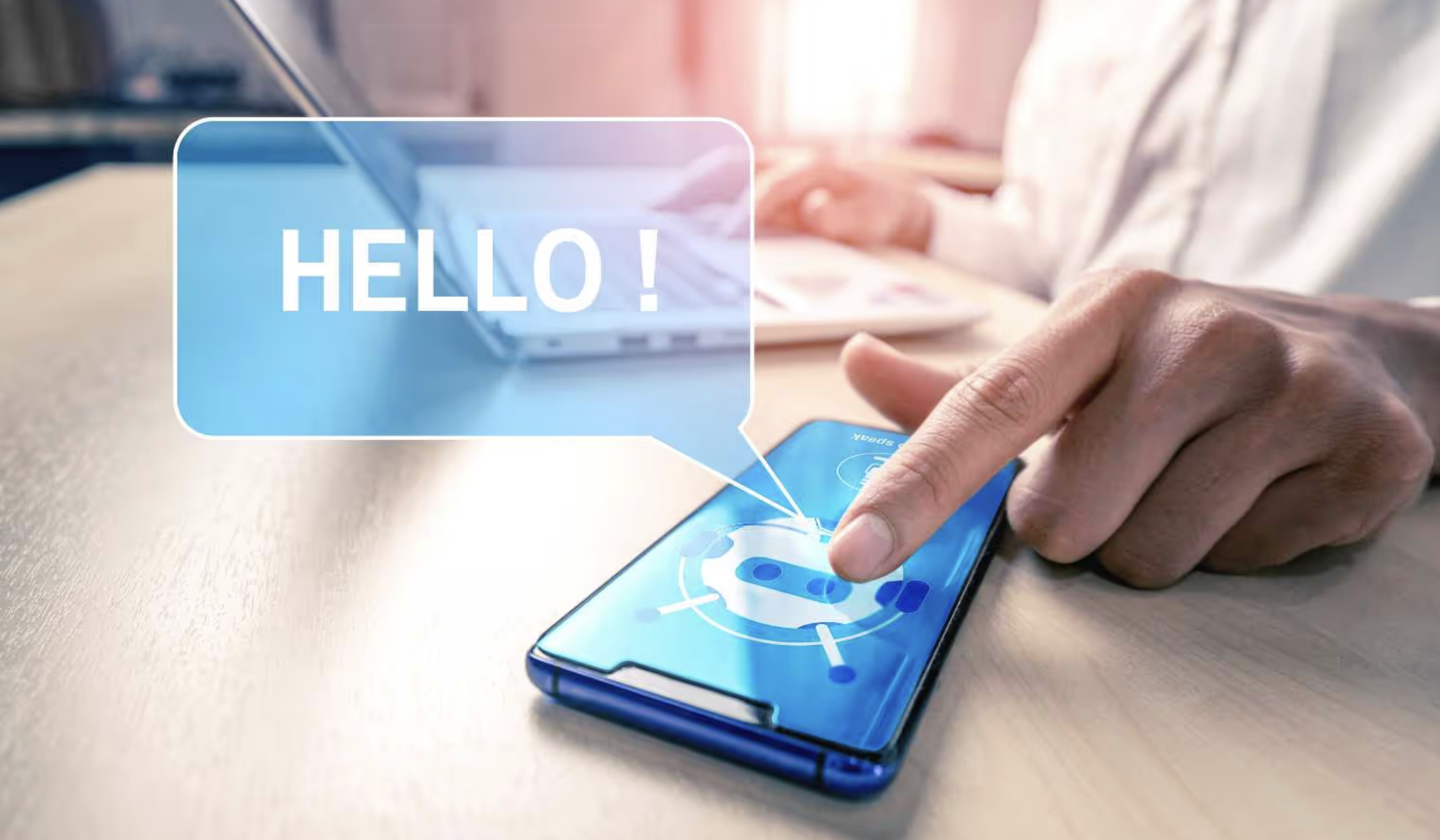 Hand tippt auf Smartphone mit Chatbot-Symbol; Sprechblase „HELLO!“ erscheint.