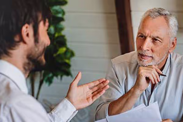 Older man sitting across from young man discussing paperwork