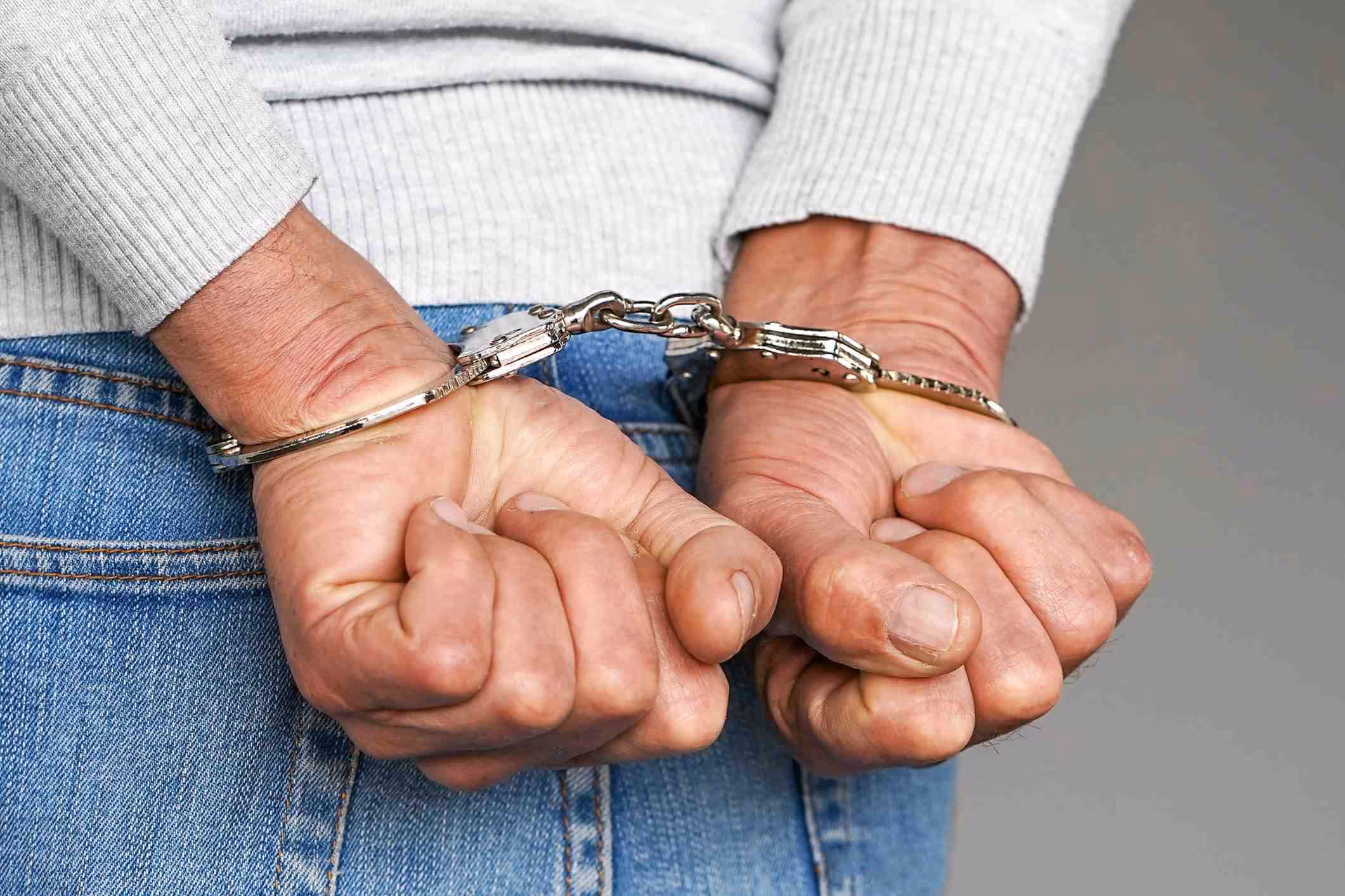 Criminal hands locked in handcuffs