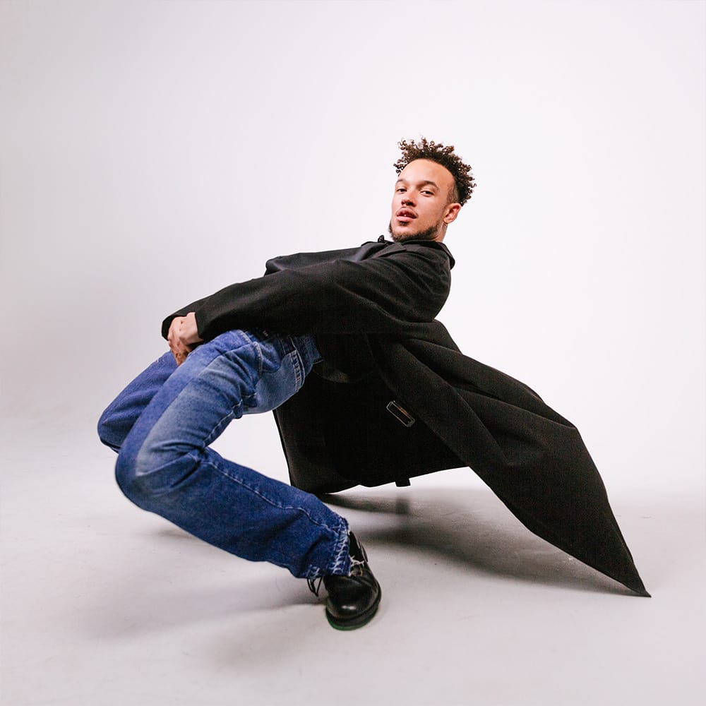 the artist Vincent Darby with his black jacket flowing to the back in a white background