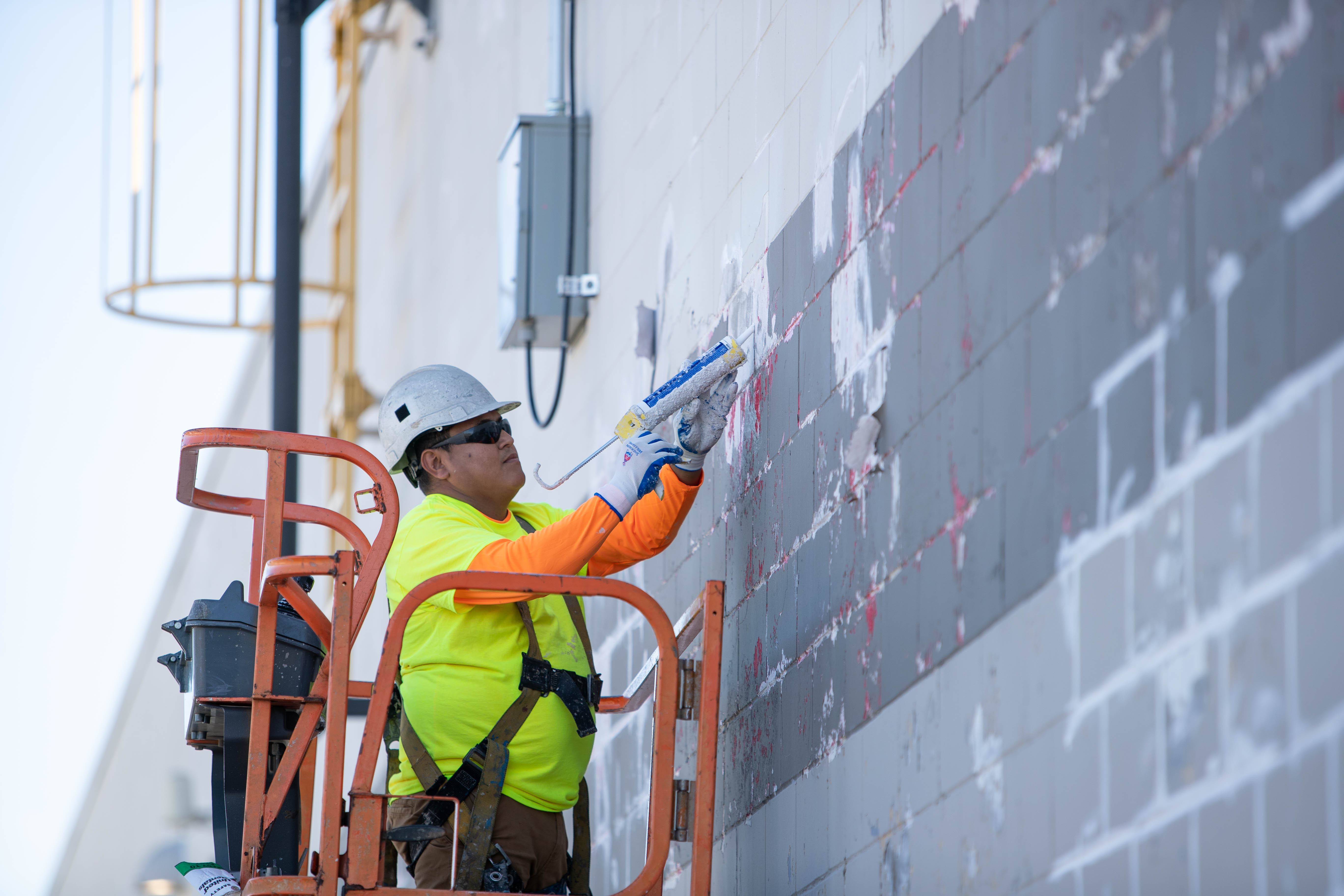 FCP Services crew member sealing an exterior wall from a lift