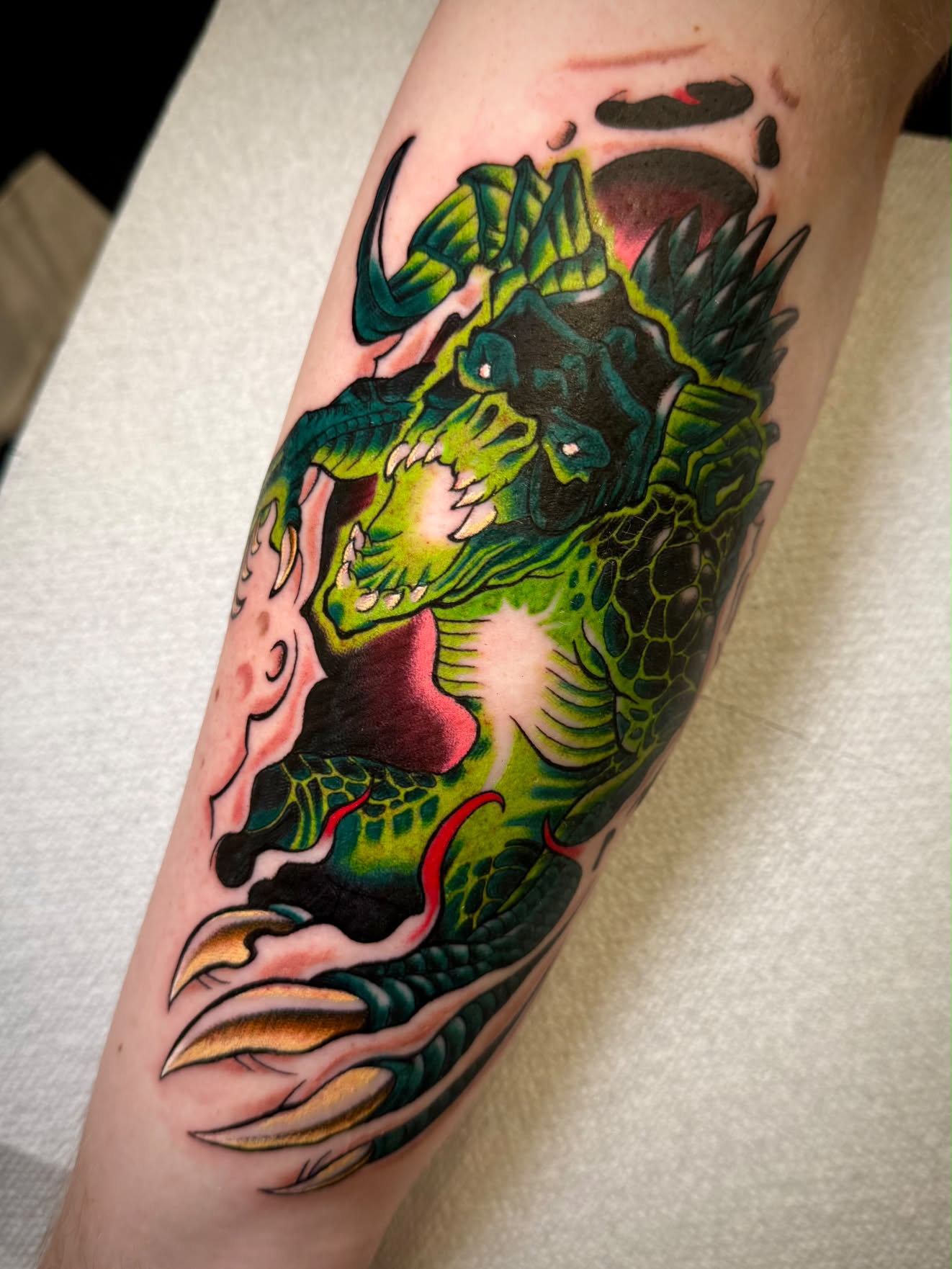 Green neo-traditional dragon forearm tattoo
