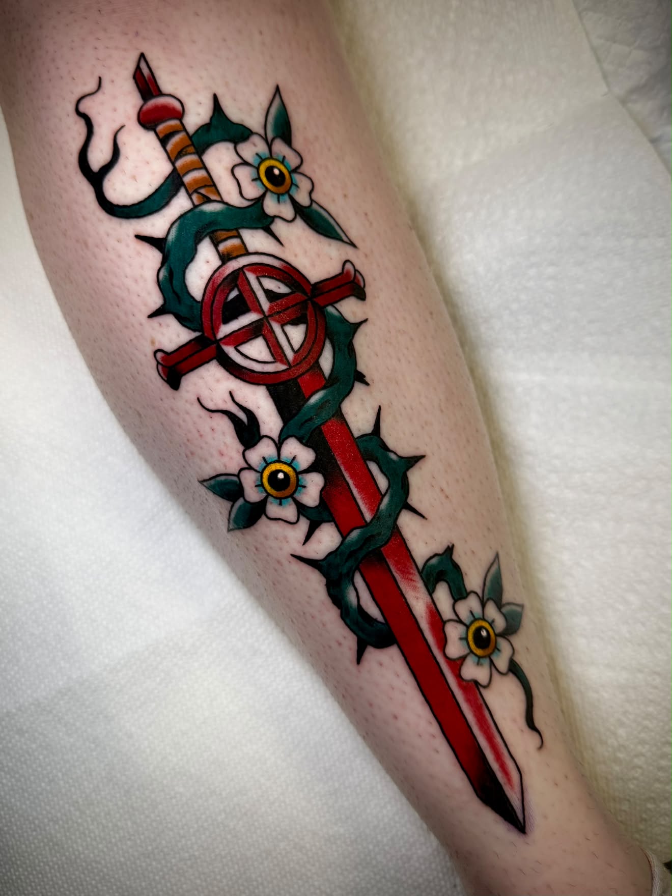Traditional red sword tattoo with thorny vine and flowers