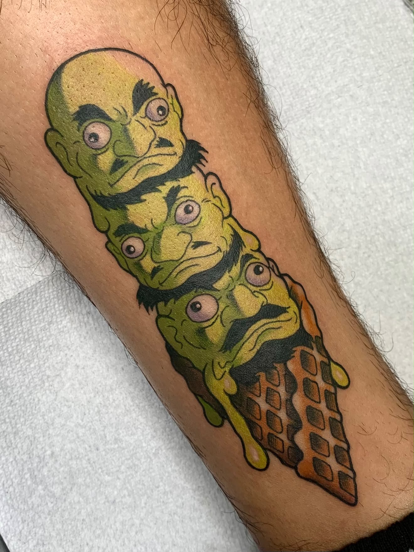 Melting ice cream cone of green cartoon heads tattoo