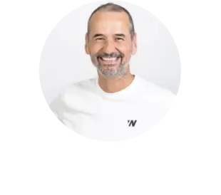 Smiling middle-aged man with a beard wearing a white shirt against a light background.