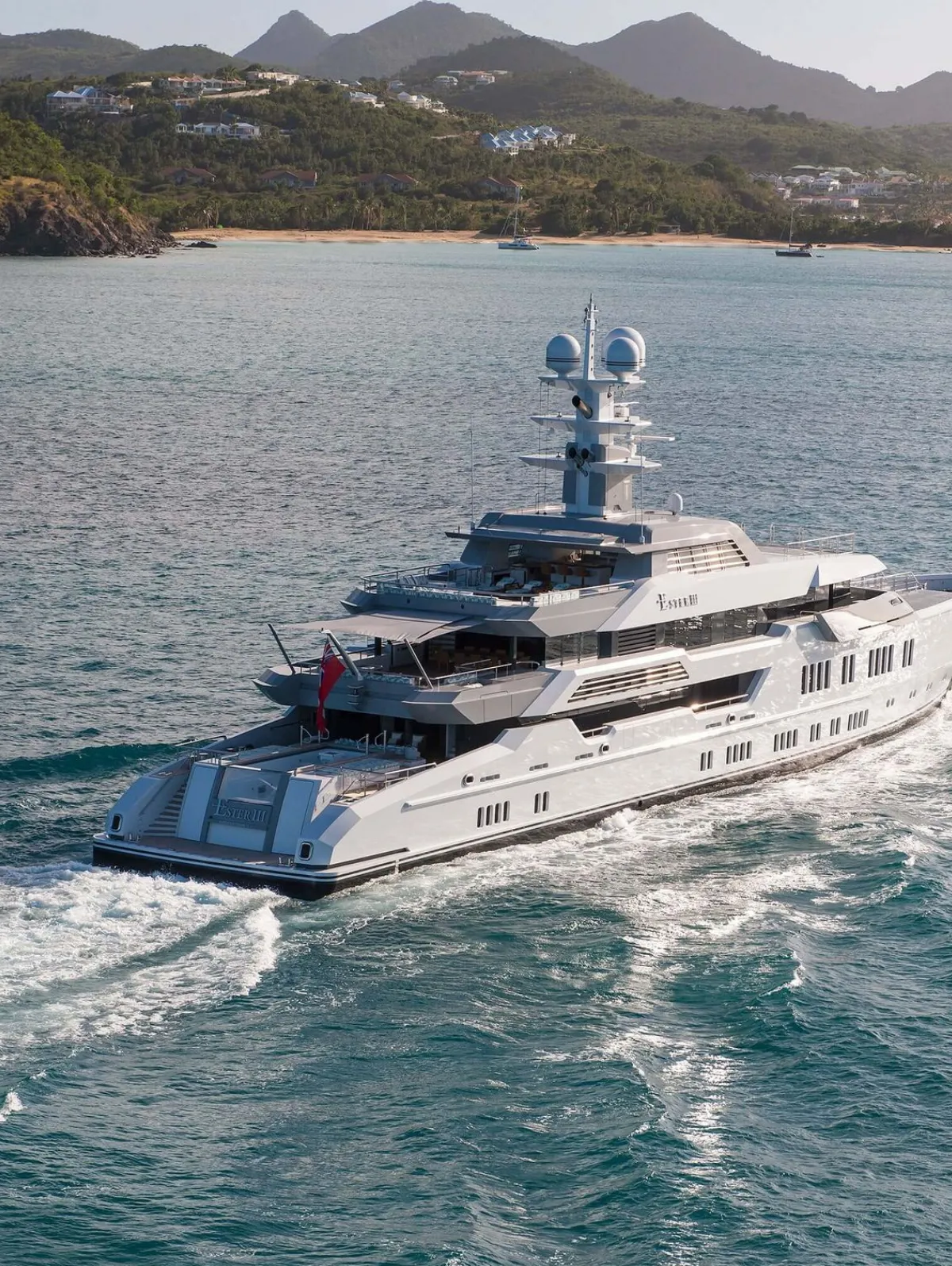 A private super yacht cruising through the crystal clear waters of the mediterranean with Greece in the background.
