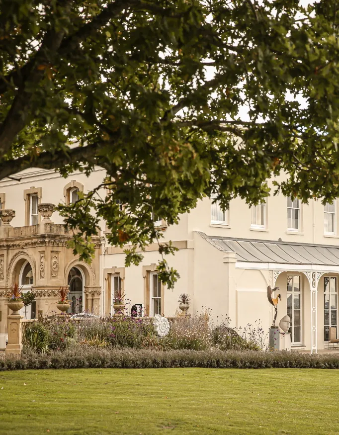 Exterior view of Lympstone Manor where a part of Lympstone Manor is covered by a tree.