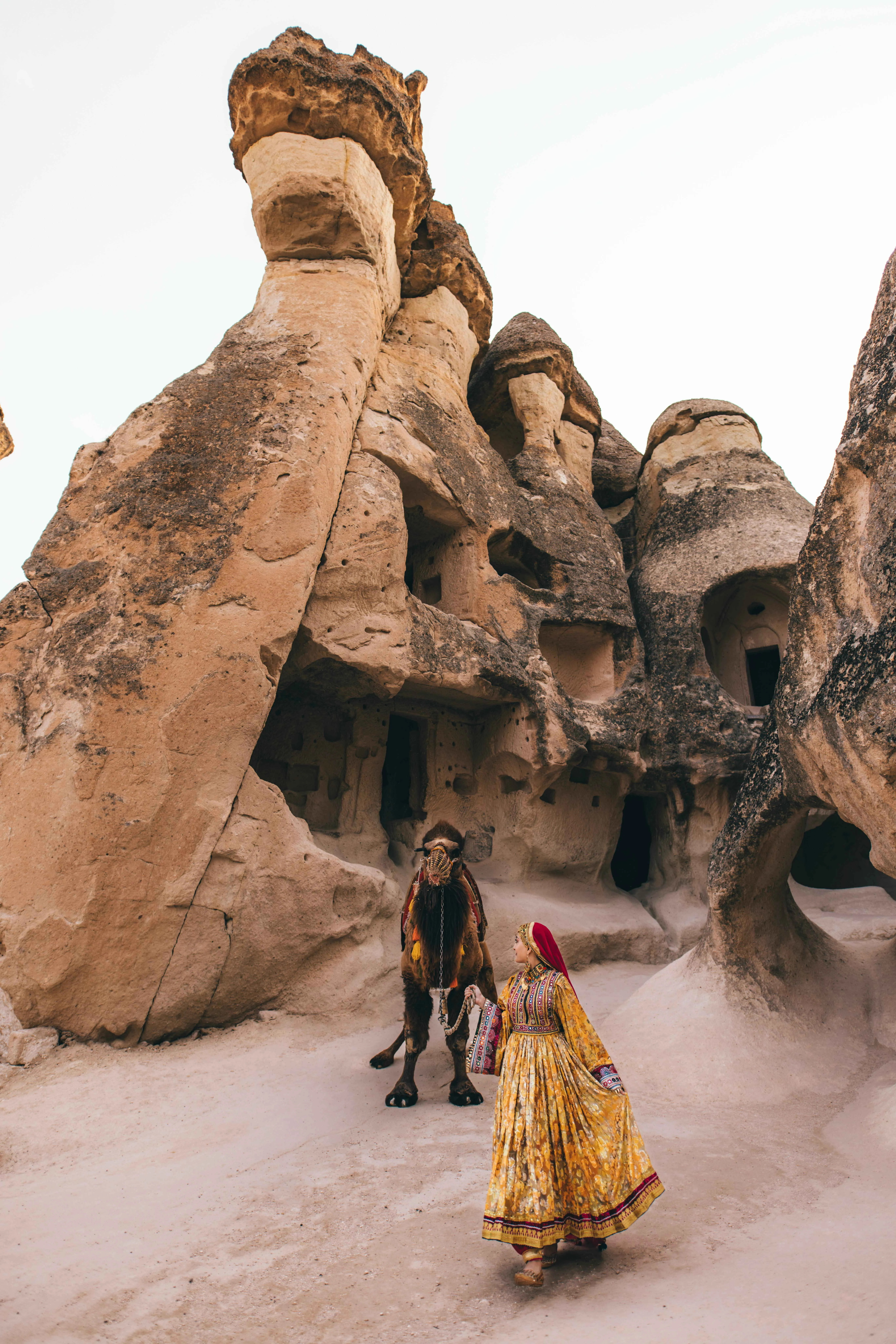 A woman in traditional clothing leading a camel in an ancient city near Cappadocia in Turkey.