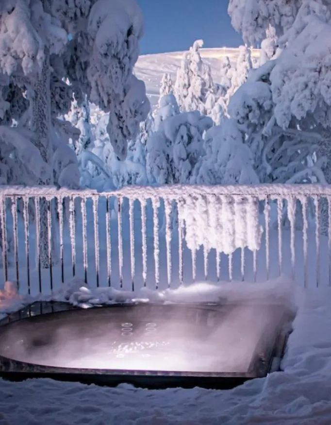 Jacuzzi at Villa Viima with a view over the snow-covered forest.
