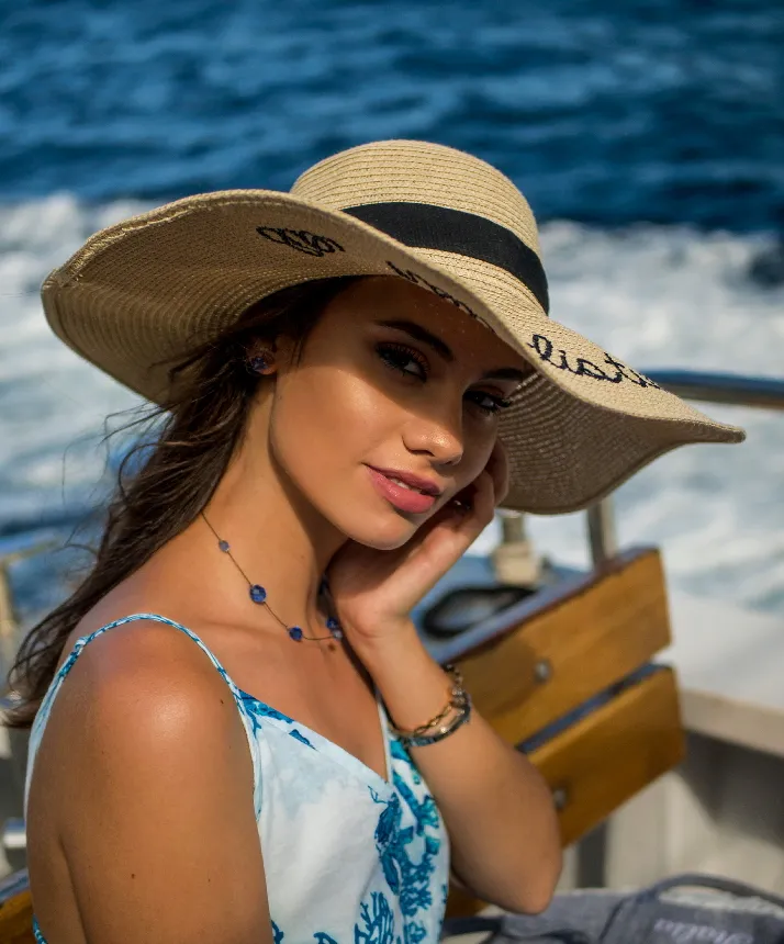 A young lady with a hat protecting her skin against the sun on a private yacht travelling through the mediterranean.