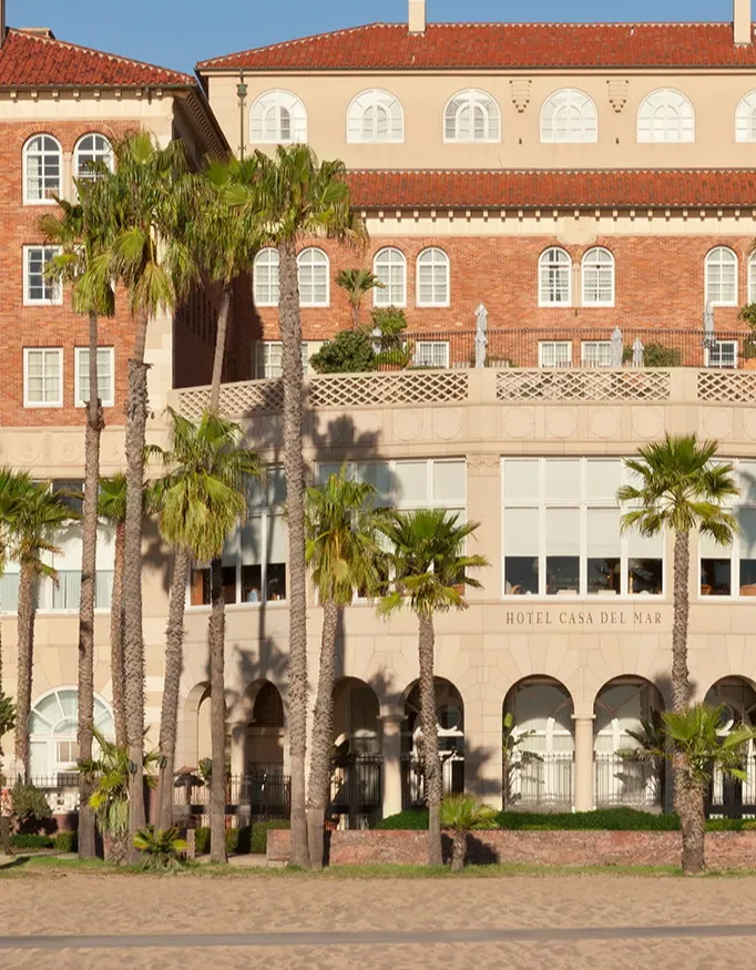 The exterior of Hotel Casa del Mar with palm trees in front of the hotel.