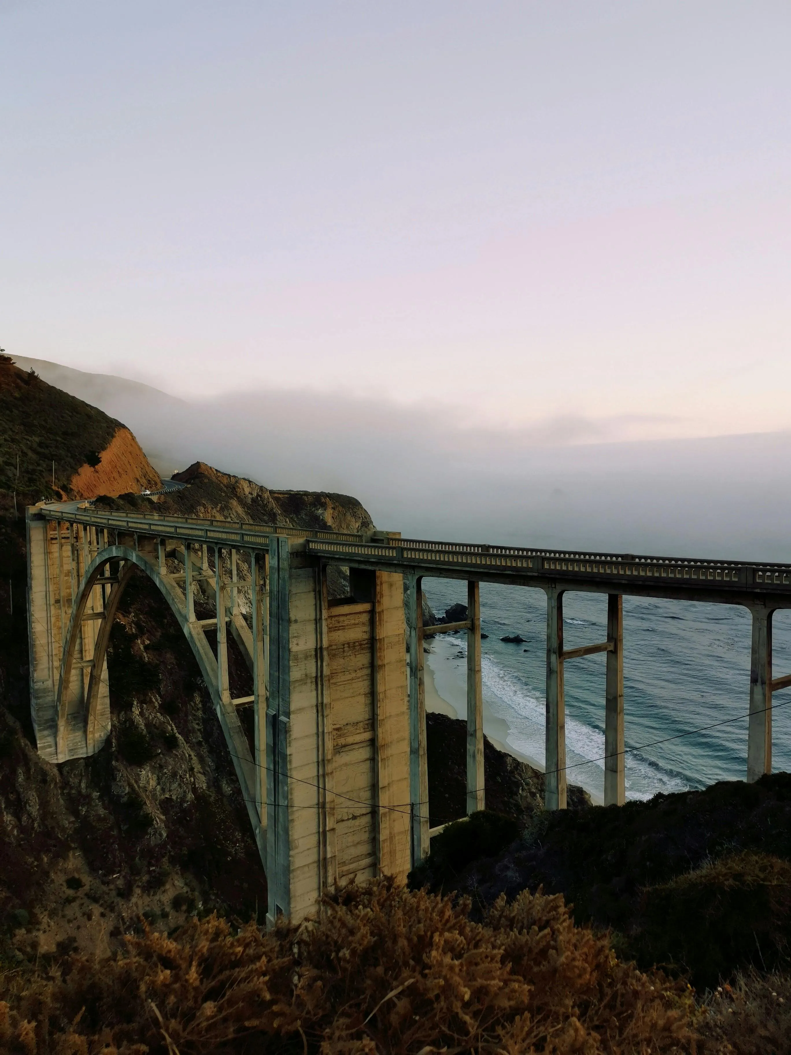 The Bixby Creek Bridge and the ocean in the background during sunset.