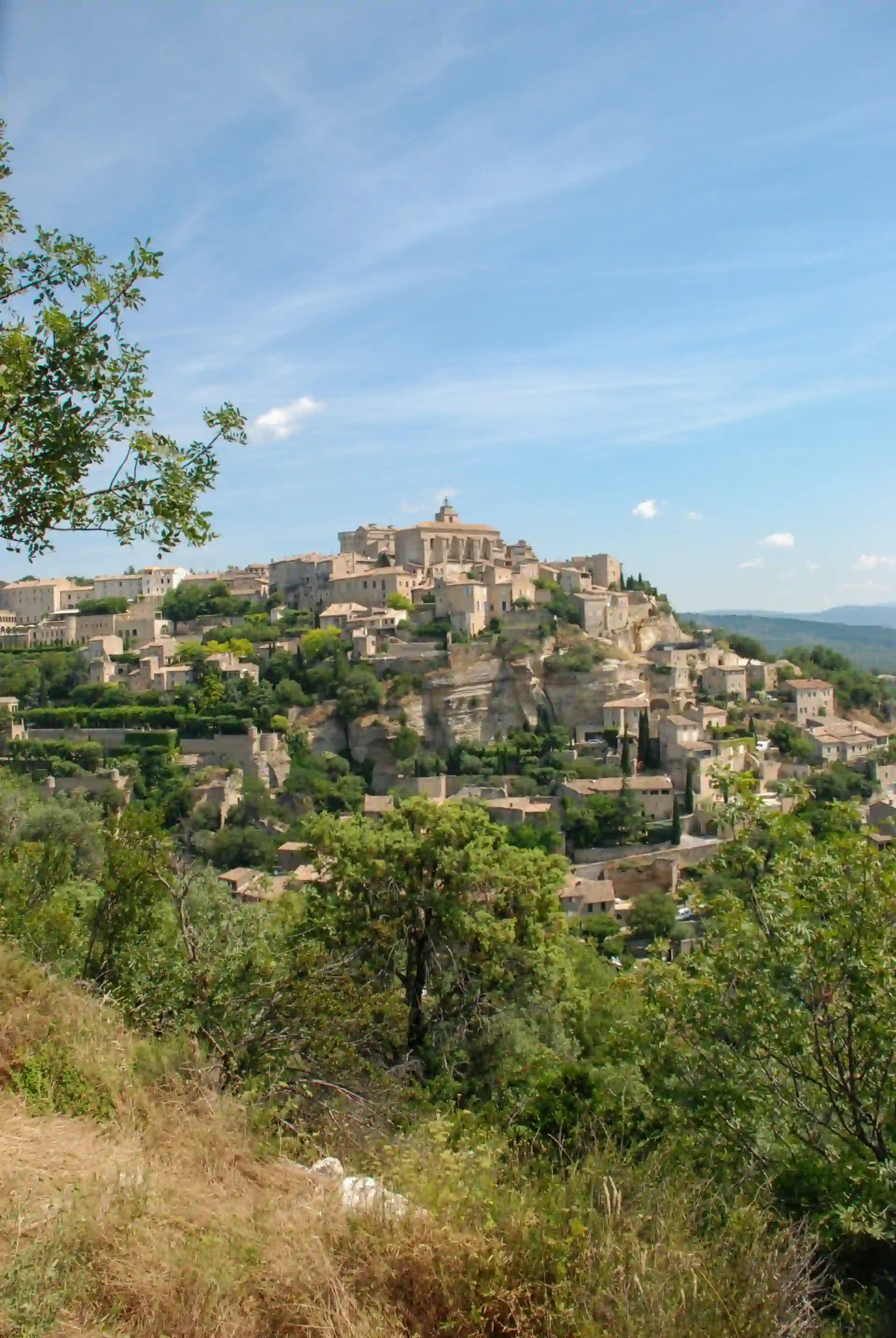 An old ancient town in the rolling hills of the Provence in Southern France with a blue sky viewed from another hill.
