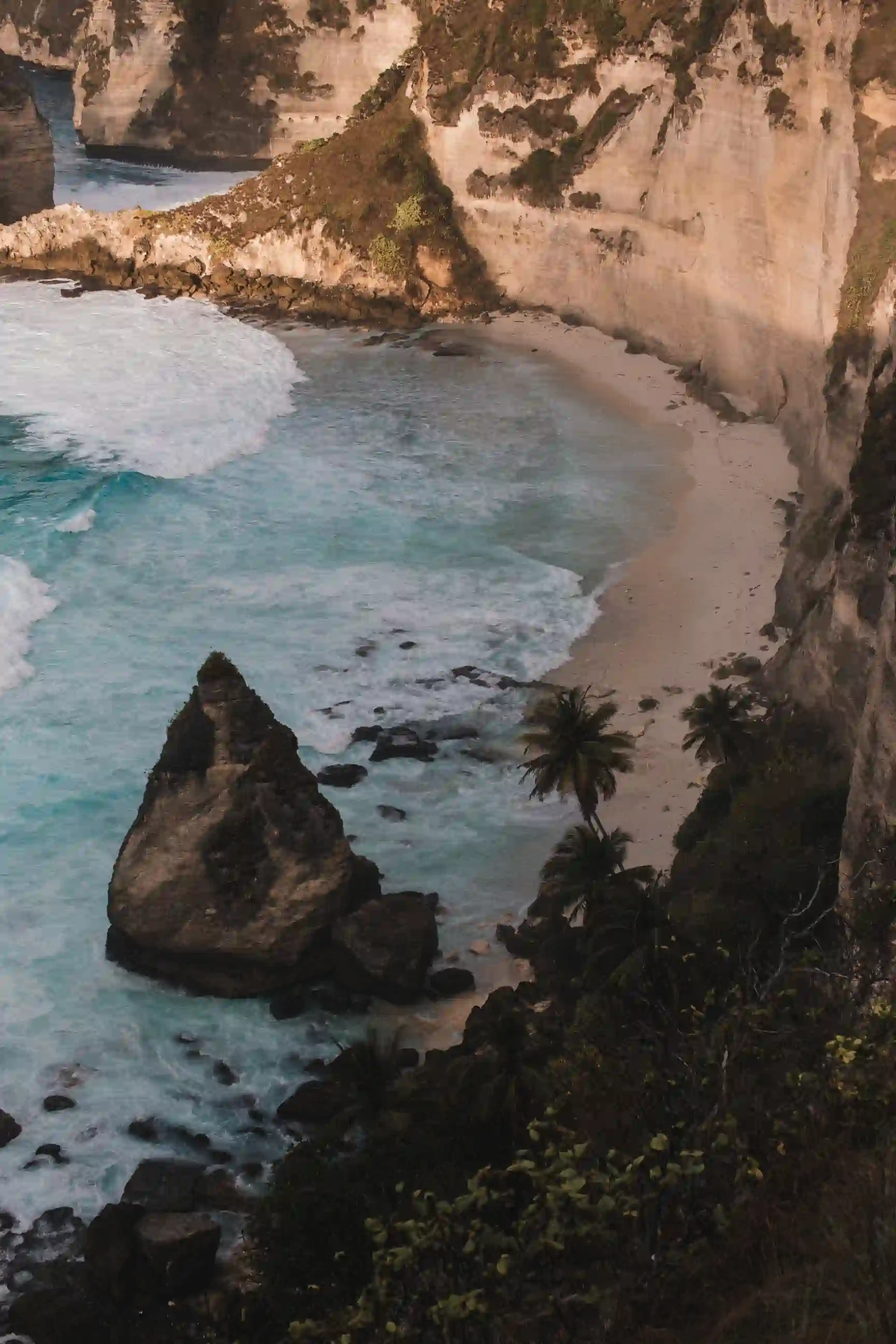 A cliff from above with the sea and waves in a sunny and warm climate.