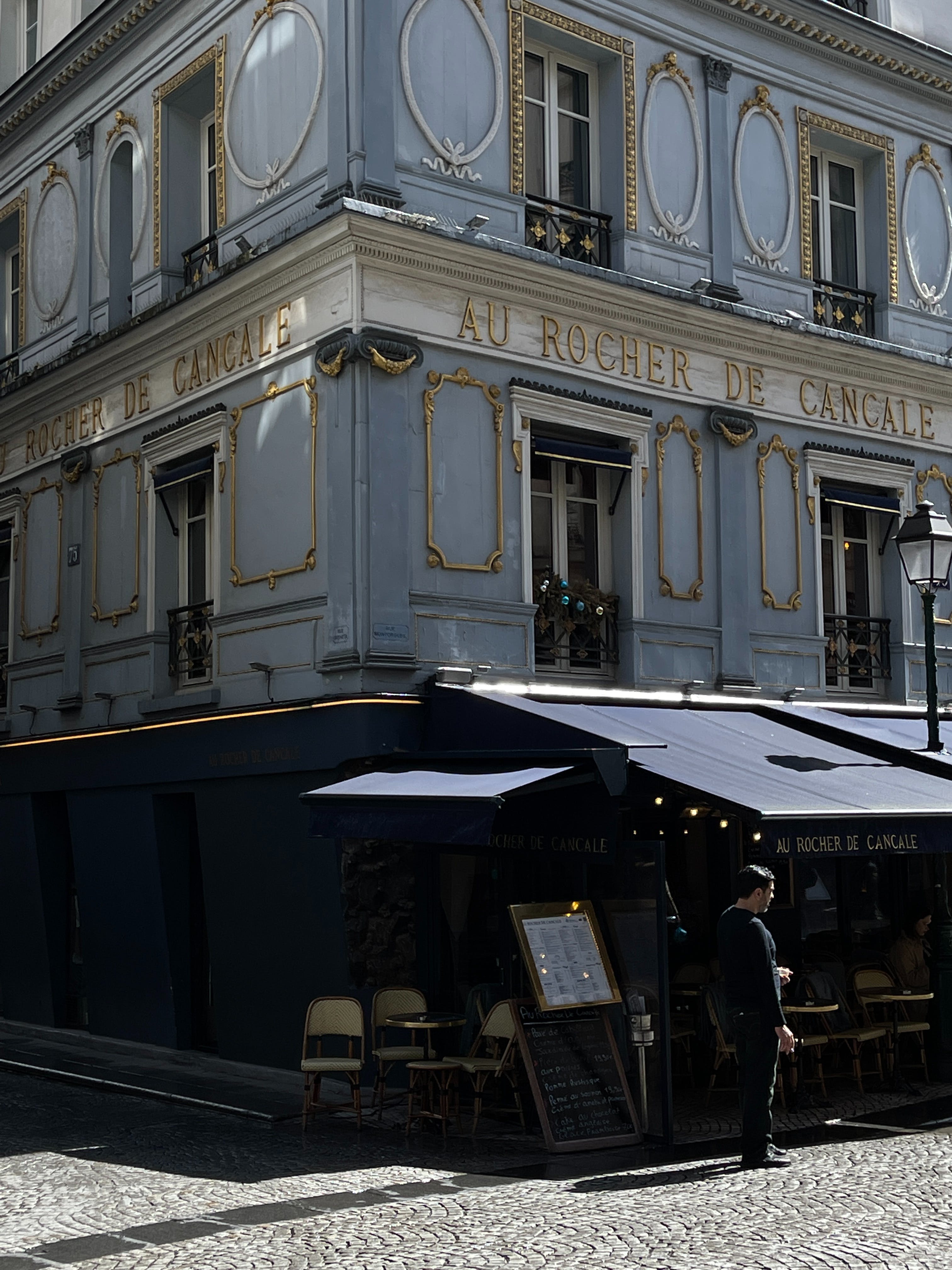 Front of a small cafe in a baroque building in Paris.