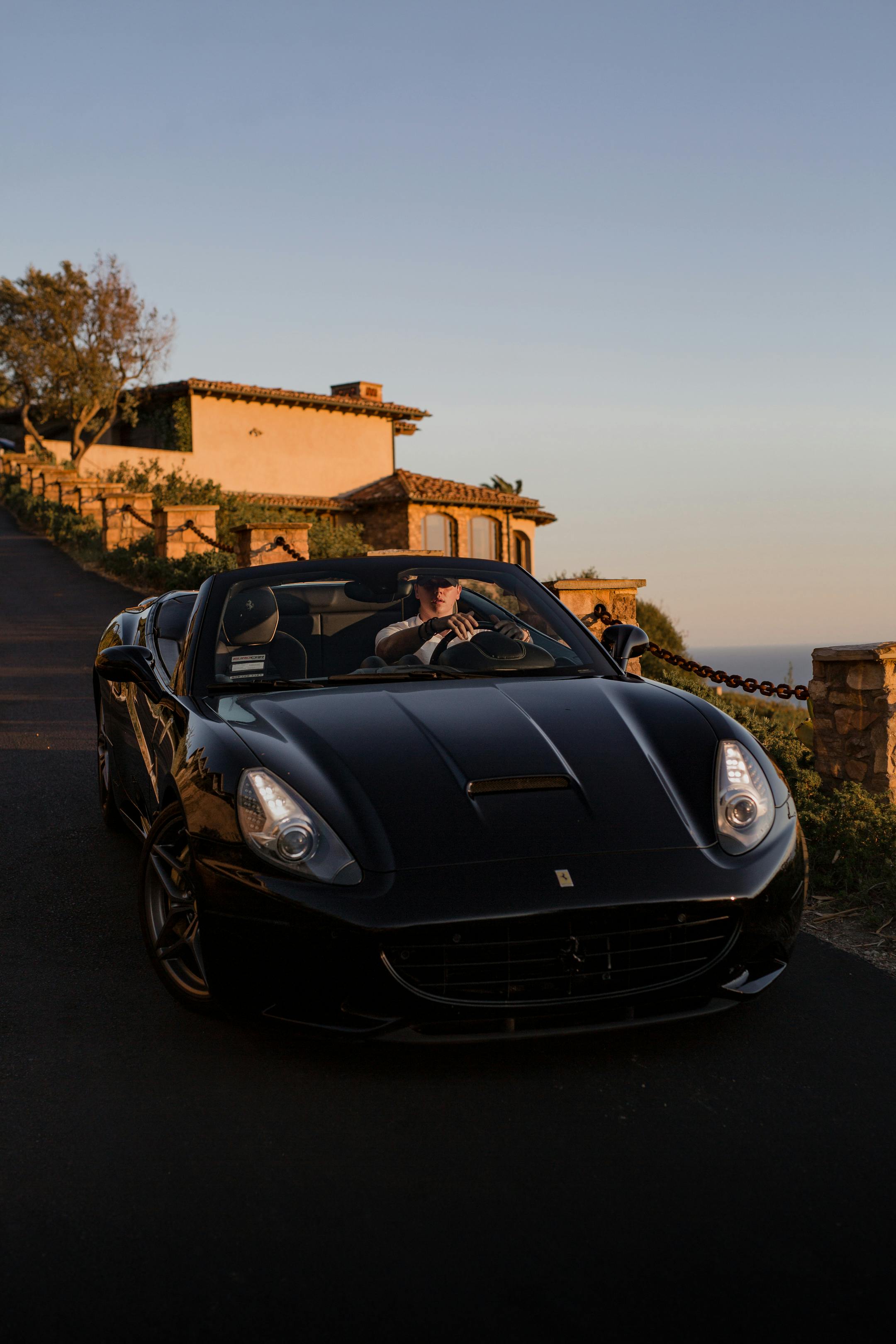 Lamborghini on the road and the ocean in the background. The sun is setting, giving a warm glow.