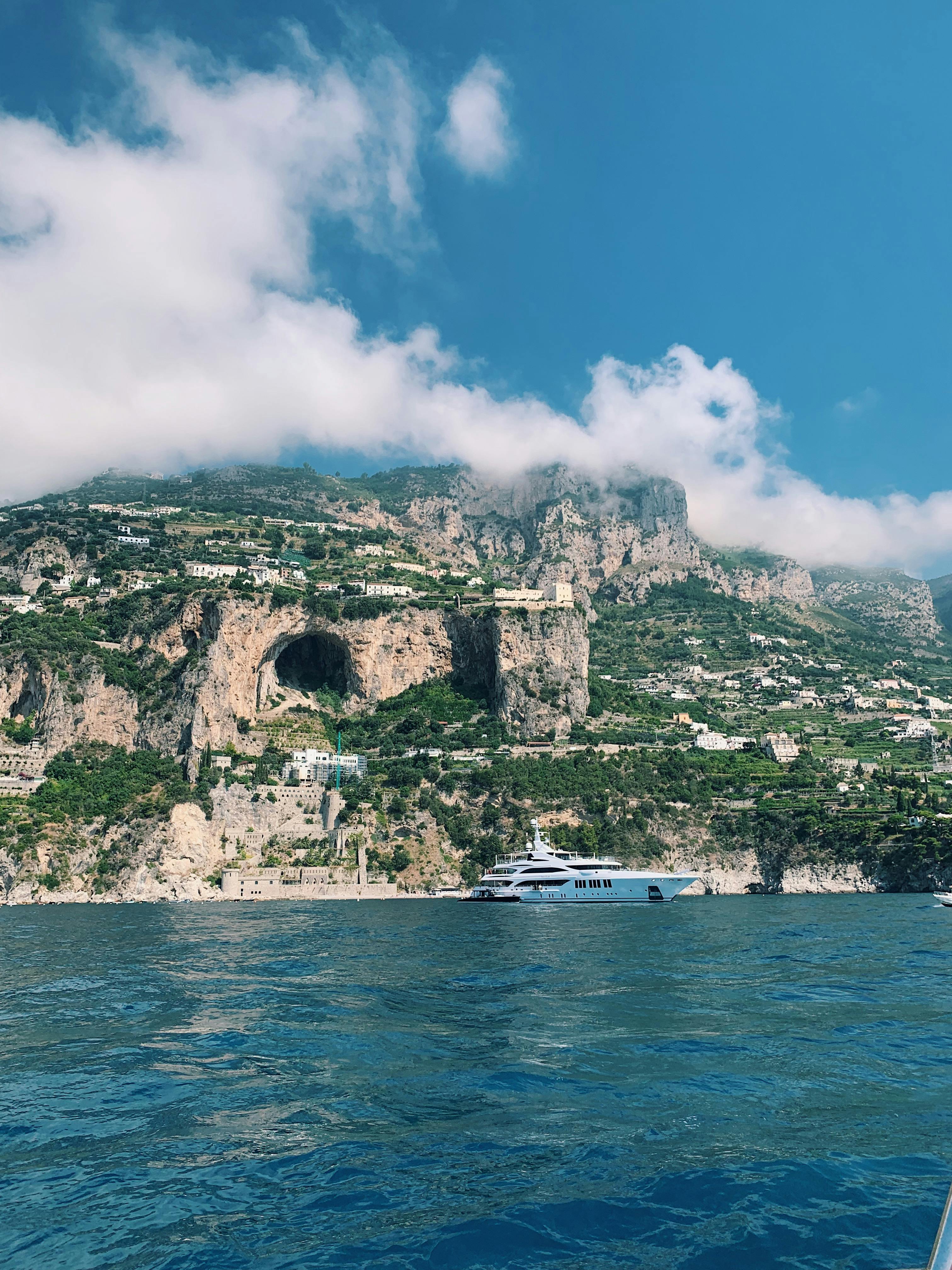 Coastline of Amalfi with a yacht in front of it.