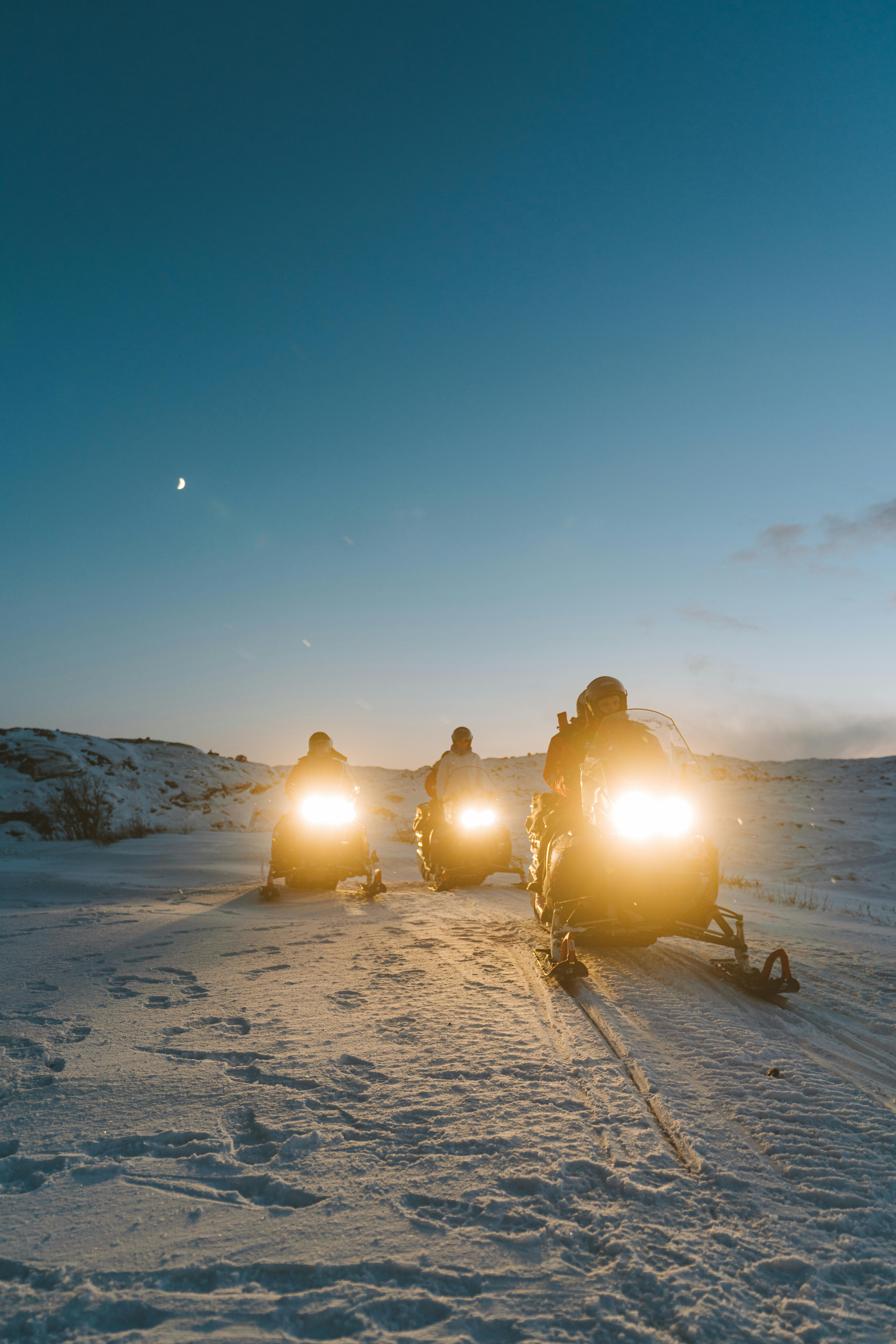 Three snowmobiles during sunrise